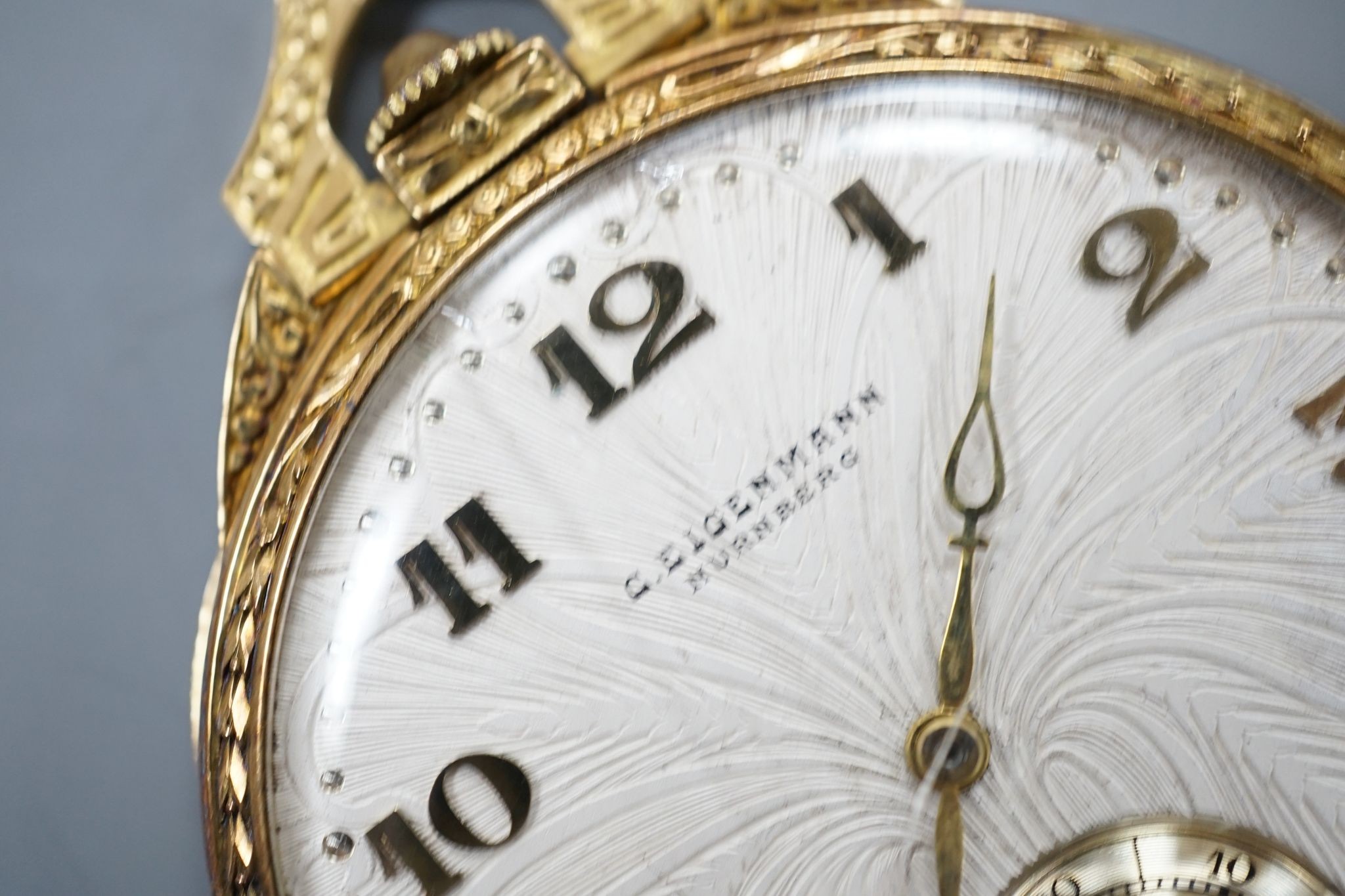 A continental engine turned 750 yellow metal open face dress pocket watch, retailed by Eigenmann, Nuremburg